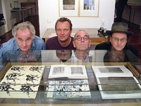 Fünf in einem Buch Farbphotographie: vier Köpfe hinter Vitrine, die sich teilweise spiegeln