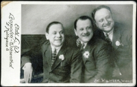 Schwarz-Weiß-Photographie: drei Männer sitzen lachend nebeneinander