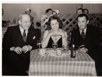 Hermann Leopoldi, Helly Möslein und Arthur Berger, USA ca. 1943. Wienbibliothek im Rathaus Schwarz-Weiß-Foto: Frau und zwei Männer an gedecktem Tisch mit kariertem Tischtuch sitzend