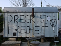 Farbphotographie: Container mit Rauchfang, davor Holzbank