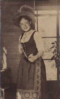 Schwarz-Weiß-Photographie: Mädchen im Dirndl und Trachtenhut rührt in einer Schüssel