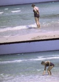 Frau am Strand, mit den Füßen im Wasser stehend
